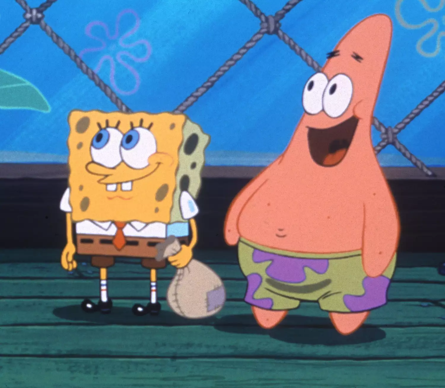 SpongeBob SquarePants and Patrick Star standing together in a cheerful moment on the Krusty Krab's wooden floor. SpongeBob is smiling while holding a sack, and Patrick is joyfully looking on with his signature wide smile. The background features the ropes and ocean-themed wall décor of the Krusty Krab.